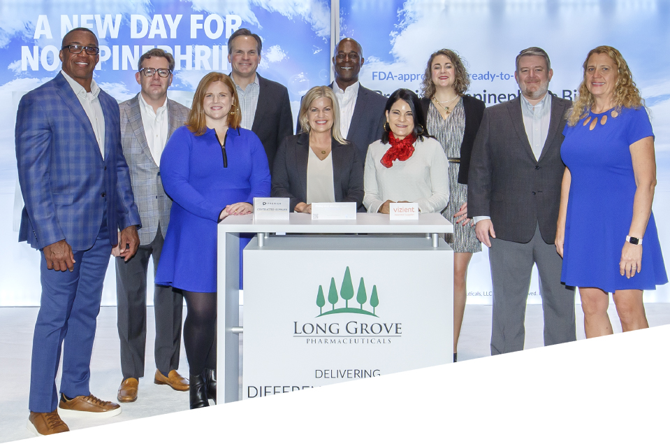 Long Grove Sales Team standing at their tradeshow booth behind a podium with the Long Grove logo front and center